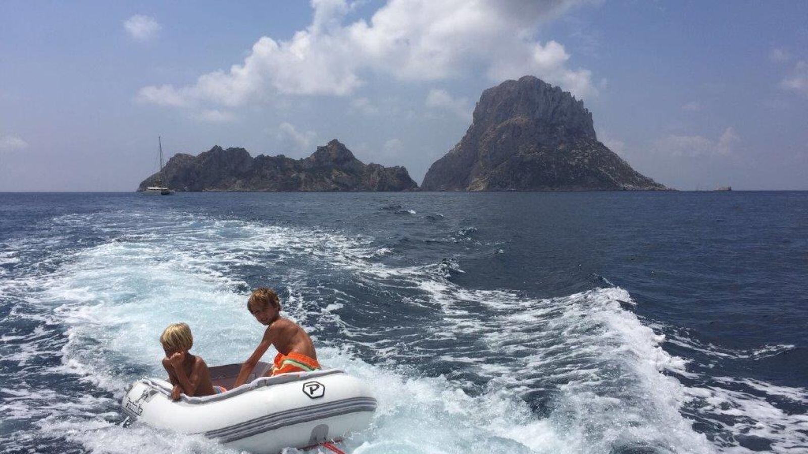 Smiling children in a dinghy while sailing in Ibiza with our boat for rent